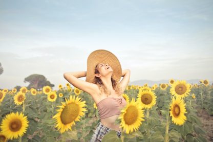 a young lady happily standing in a sunflower field surrounded by bloomed sunflowers