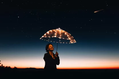 A woman is looking at the umbrella which is illuminated
