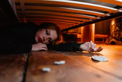 a lady is lying under bed with tablets showing her poor mental health
