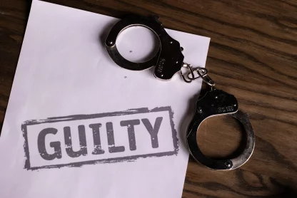 Handcuffs lying on a paper , in which its written "Guilty"