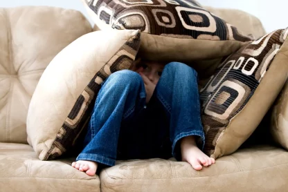A boy is hiding in a bunch of pillow die to Disruptive Mood Dysregulation Disorder