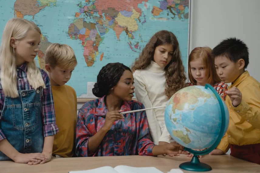 a teacher is showing globe to children